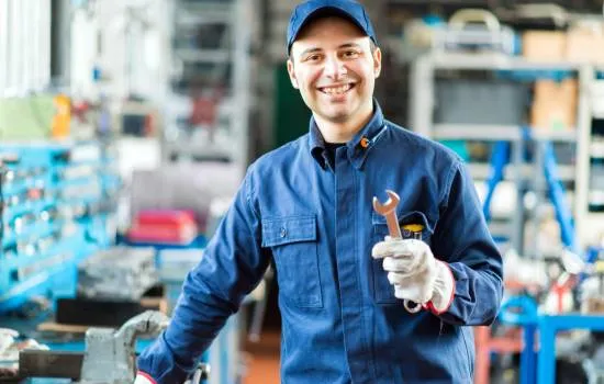 Joven mecánico sonriendo en un taller moderno, ideal para quienes desean aprender mecánica de forma práctica.