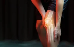 Persona sujetando su rodilla con una representación gráfica de huesos, ilustrando el dolor articular y el apoyo de la Inteligencia Artificial.