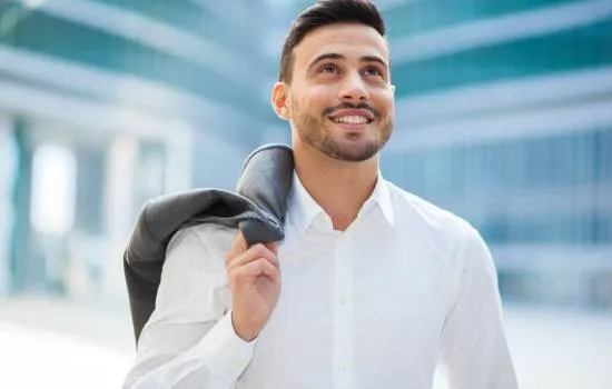 Hombre sonriente caminando con confianza en un entorno urbano moderno Aumenta tu confianza