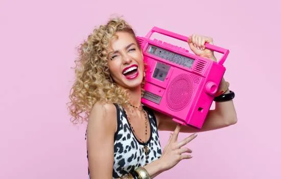 Mujer alegre con estilo retro sosteniendo una radio rosa, disfrutando de su música favorita con entusiasmo