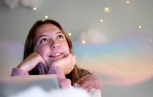 Joven mirando al cielo con una sonrisa mientras una nube de colores la envuelve, evocando la interpretación de sueños.