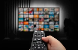 Persona apuntando un control remoto hacia una televisión con muchas opciones en la pantalla