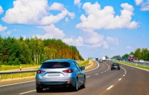 Auto familiar circulando por carretera segura y despejada bajo un cielo azul, ideal para ilustrar cómo protege a tu familia mientras viajas.