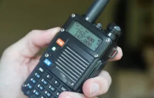 Dispositivo portátil de radio frecuencia sostenido por una mano, mostrando su pantalla y botones con claridad.