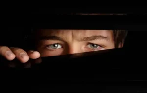 Rostro de una persona observando discretamente a través de una rendija, simbolizando la sospecha de que tu celular tiene micrófono espía.