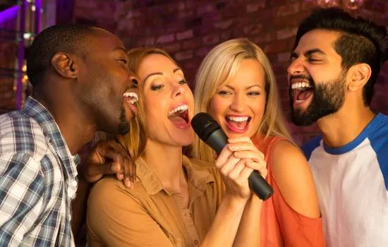Grupo de amigos cantando juntos con micrófono, disfrutando de un animado momento de karaoke en casa.